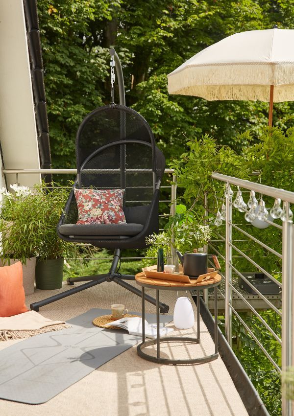 Boho Balkon mit Hängesessel, Lichterkette und Sonnenschirm Boho Balkon mit Hängesessel, Lichterkette und Sonnenschirm