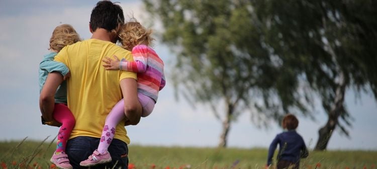 Papa mit seinen Kindern auf einer Wiese